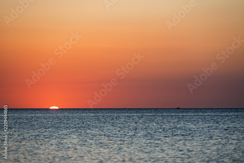 First rays of the rising sun appearing over the ocean horizon at dawn.