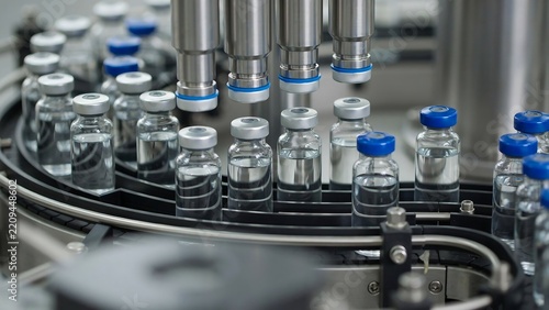 Vaccine production line with glass vials moving on a conveyor belt in a pharmaceutical facility