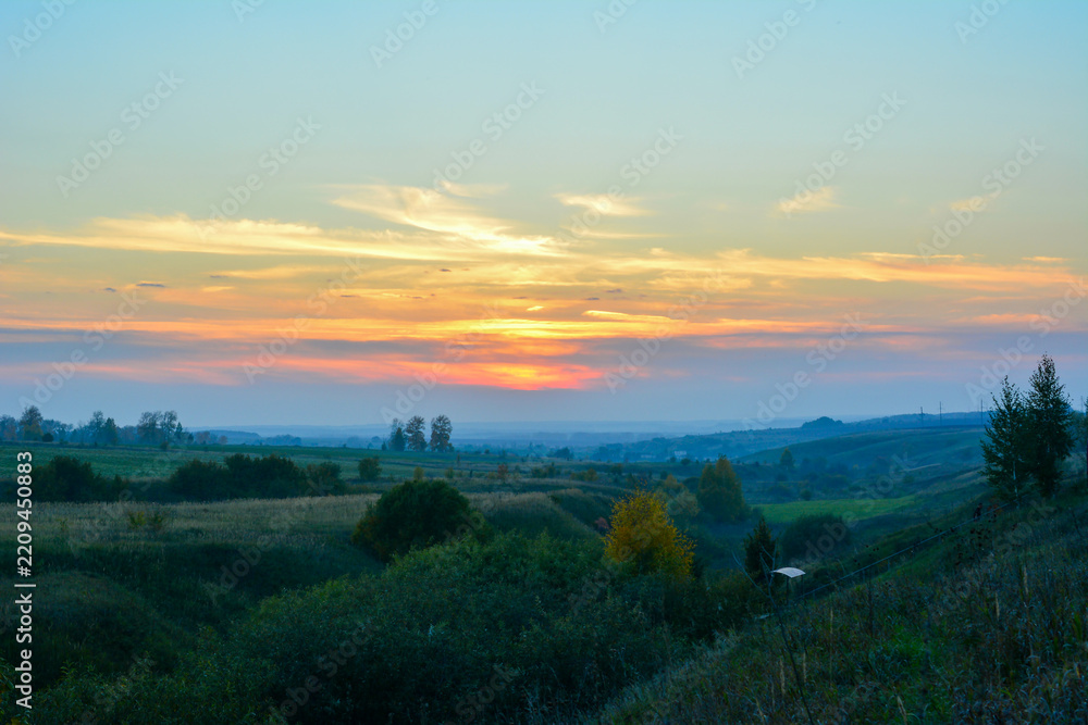 Fototapeta premium Sunset with blue and orange clouds over a Rolling Valley Landscape