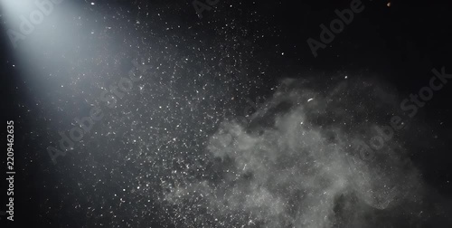 Dramatic light beam illuminating dust particles and smoke against a dark background.