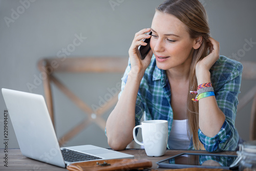 Young Woman Working on Laptop and Talking on Phone