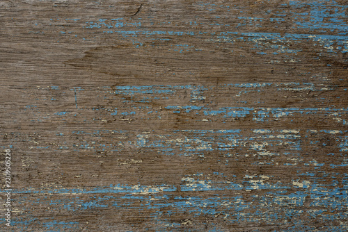 Weathered wooden surface with faded blue paint, exposed wood grain, scratches, and distressed texture, creating a rustic background