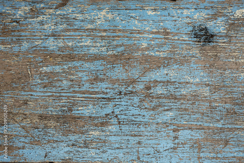 Weathered wooden surface with faded blue paint, exposed wood grain, scratches, and distressed texture, creating a rustic background