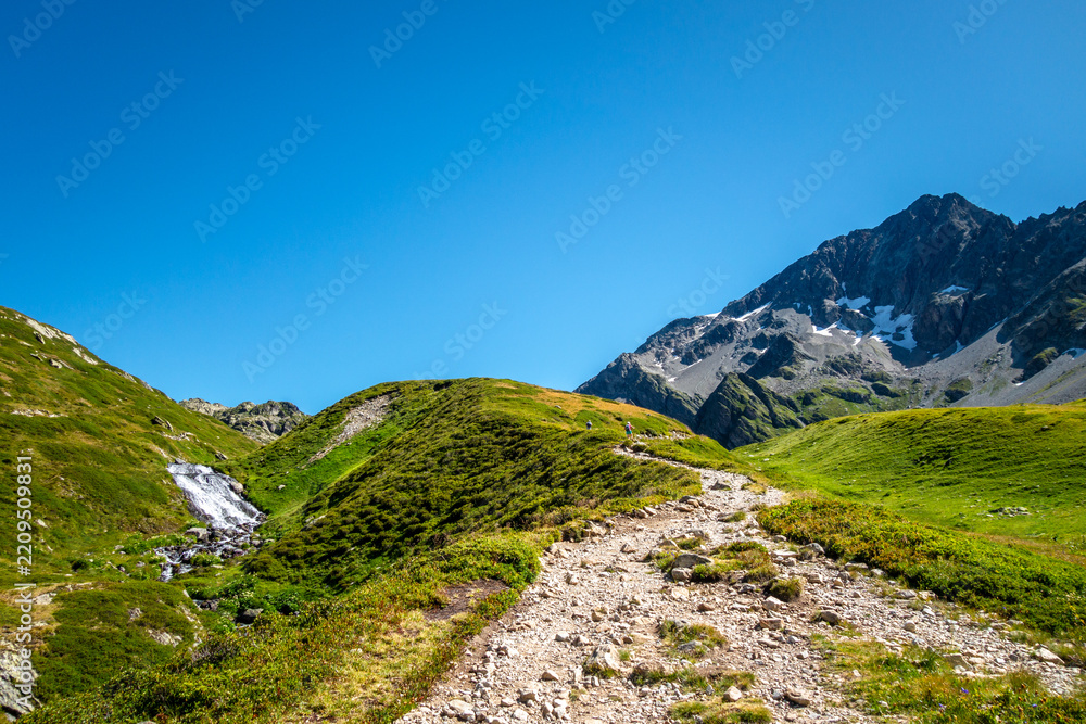 Obraz premium Hiking trail through alpine meadow at Contamines Montjoie, France