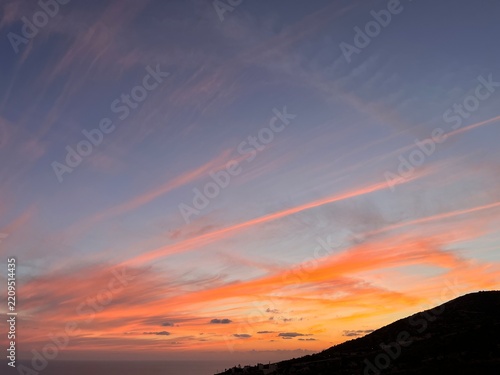 Beautiful dramatic sunset sky over dark coastal hills and sea landscape