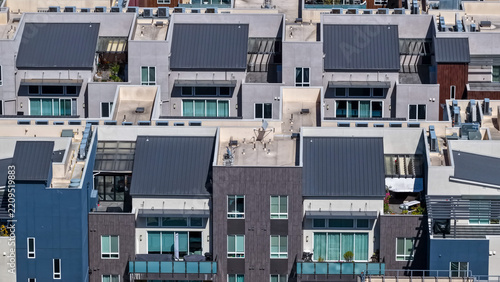 Aerial view of modern residential apartment buildings with dark metal roofs, balconies, and large windows in a dense urban neighborhood in Fremont, California, United States.
