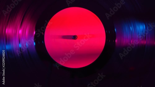 Vinyl record spinning under colorful light