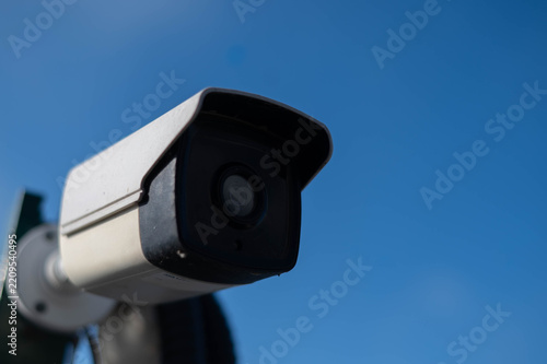 Security surveillance camera against blue sky