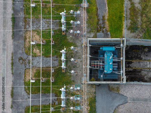 Aerial view of an electrical substation with high-voltage equipment, transformers, and power lines set within a fenced industrial area in Andalsnes, More og Romsdal, Norway.