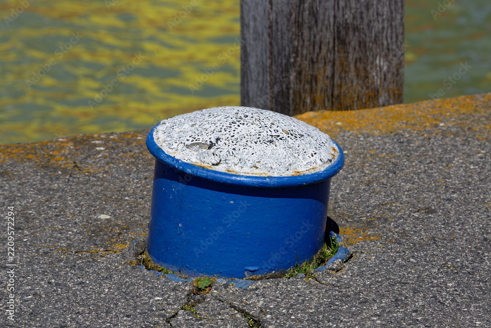 Obraz premium Blue bollard with weathered white top on a dock by the water