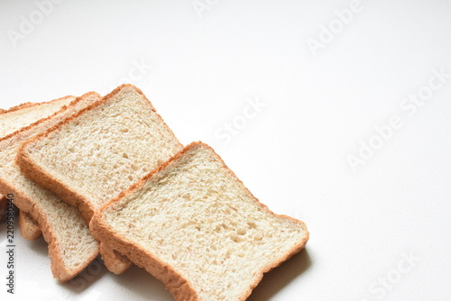 Fresh whole wheat bread slices arranged on a clean white table, showcasing healthy food, breakfast, nutrition, and everyday meal preparation.