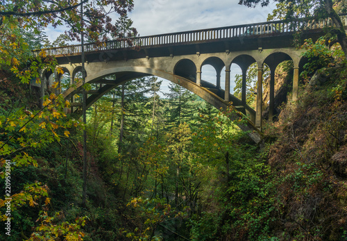 The historic Shepperds Dell concrete arch bridge carries the Historic Columbia River Highway through a forested gorge in Corbett, Oregon.