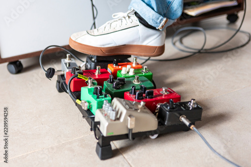 Music compositor operating guitar effects pedalboard with foot