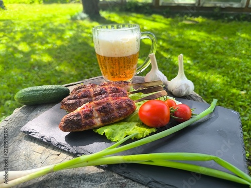fried pieces of meat with various vegetables and herbs next to a glass of beer