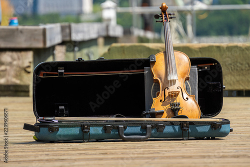 Fotografie Violin with bows in an open case on a wooden pier, ready for an outdoor musical