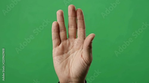 Vulcan greeting hand gesture moving fingers apart on solid green screen chroma key studio background footage