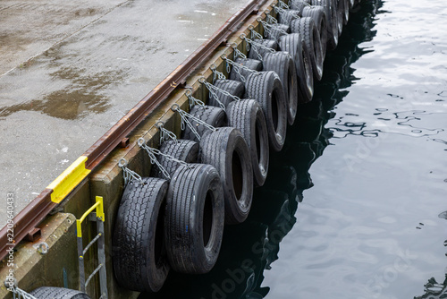 Row of Black Tire Fenders Hanging Along a Dock Beside Calm Water