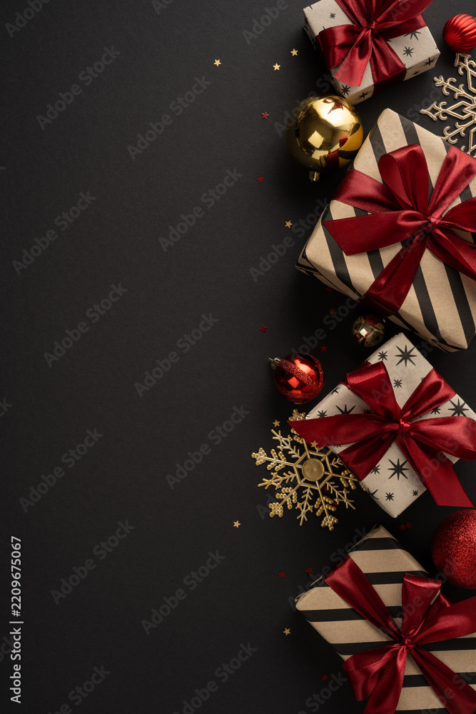 Fototapeta premium Merry Christmas and Happy New Year luxury gifts with red ribbon and gold ornament on black vertical elegant background