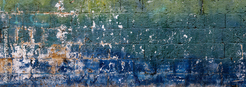 Close-up of an aged blue brick wall with peeling paint, rough texture, exposed surfaces, and rustic urban character.