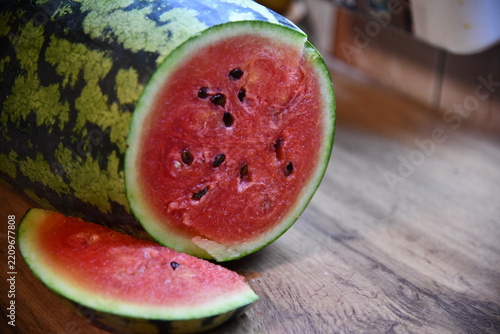 Red ripe watermelon cut in half on a pile of ripe watermelons in the field. A red cut watermelon view from