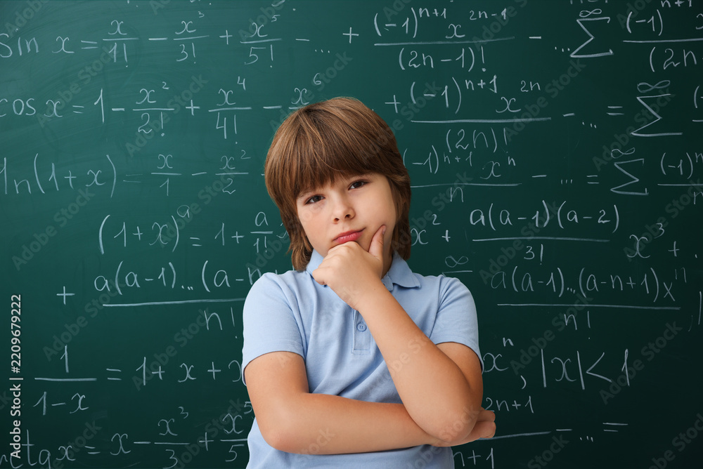 Obraz premium Puzzled student standing by green chalkboard covered with equations. Back to school