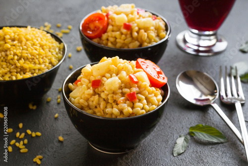 Traditional local bulgur pilaf from the Mardin city of Turkey.Designed in black bowls	on dark surface