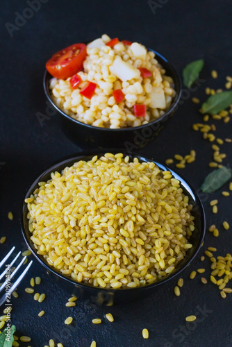 Traditional uncooked Turkish bulgur arranged in a black bowl with pilaf