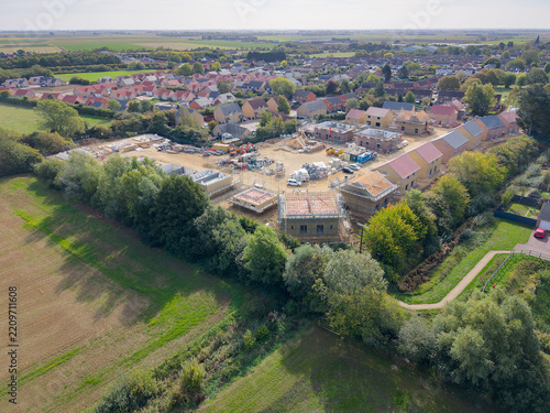 Interesting drone UAV view of a corner plot of a British housing estate accommodating both affordable and private homes. The corner plot shows the roofing timber frames.