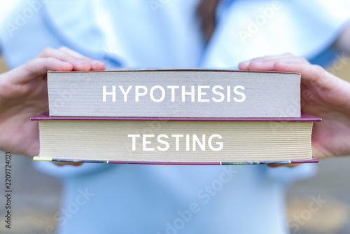 Concept of hypothesis testing. Girl holding two books sees the text HYPOTHESIS TESTING.