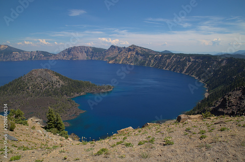 Crater Lake National Park caldera with Wizard Island under a blue sky, conveying natural majesty in a scenic landscape - Oregon, United States