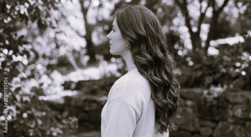 Young woman with long wavy red hair in garden.