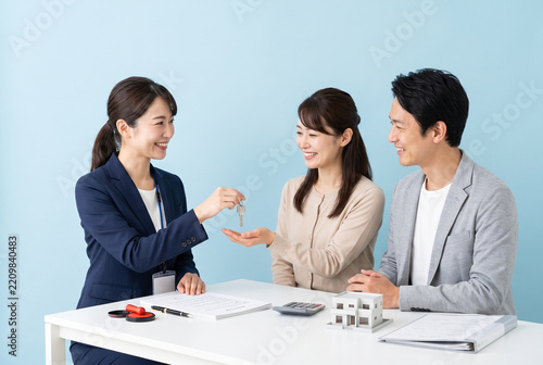 不動産会社の女性スタッフから家の鍵を受け取る夫婦 マイホーム購入や契約成立のイメージ写真