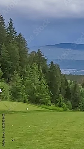 Golfers on tee box swing overlooking valley lake mountains