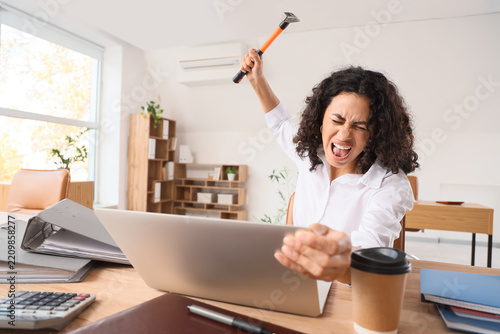 Workplace burnout and professional stress, angry woman smashing laptop with h...