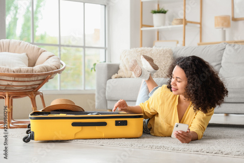 Travel planning and vacation preparation, young woman packing suitcase at hom...