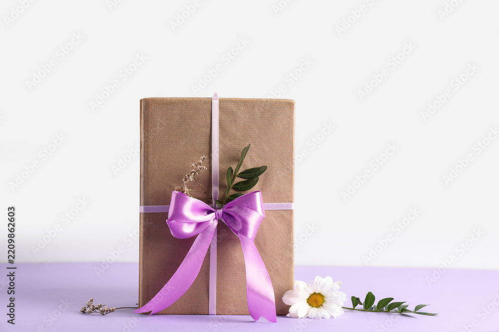 Obraz premium Gift giving and celebration, wrapped present with purple ribbon and dried flowers for birthday or holiday surprise on a clean minimalist background