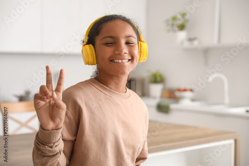 Digital childhood and music lifestyle, happy girl with yellow headphones show...