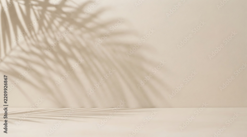 Obraz premium Palm leaf shadow cast on a plain light beige wall and surface background for product display with minimalist backdrop