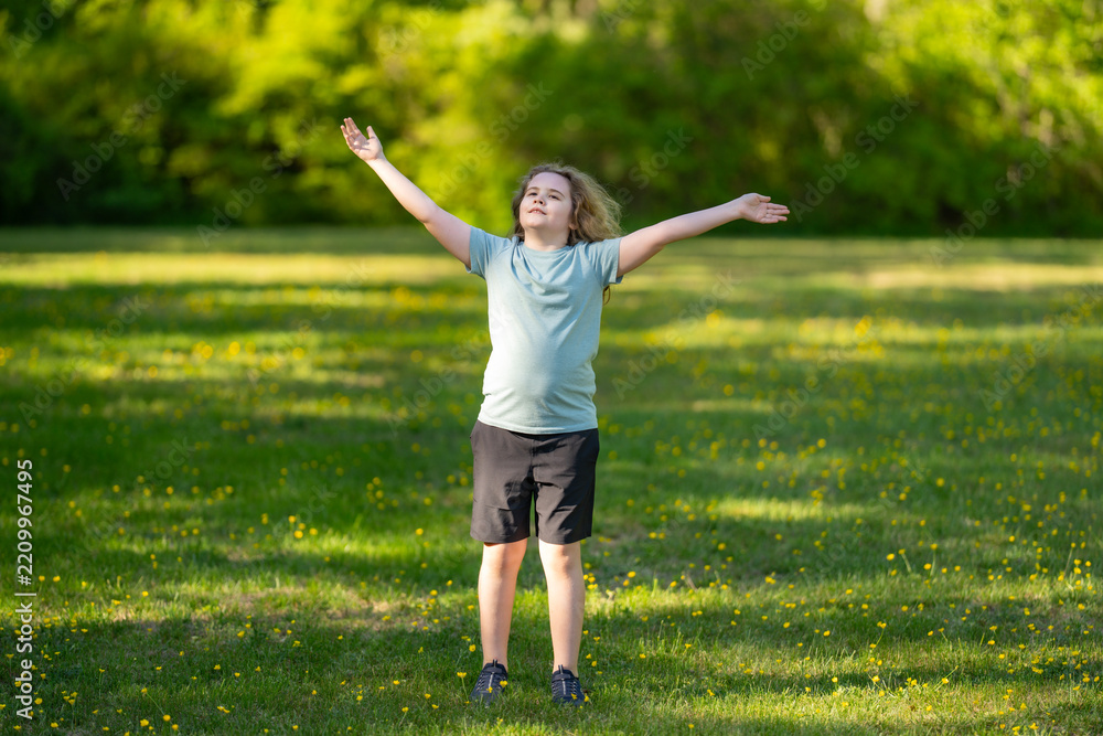Obraz premium Child enjoys mindful breathing outdoors. Child feels calm in meadow. Happy child shows joyful freedom. Peaceful child relaxes in sunshine.