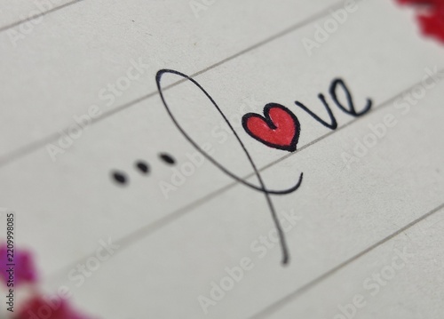 Handwritten red heart symbol in cursive script on elegant romantic notebook paper. Perfect for valentines day card designs or lovethemed graphics.