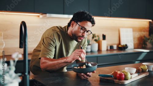 Hungry, man and bowl in kitchen with breakfast, fruit and morning nutrition for gut health benefits. Person, eating and organic food in house for meal, wellness and ingredients for balanced diet.
