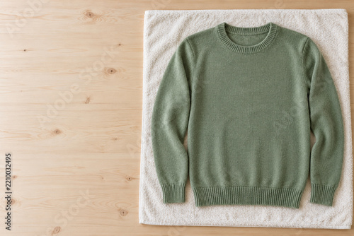 Grüner Wollpullover trocknet flach auf einem Handtuch