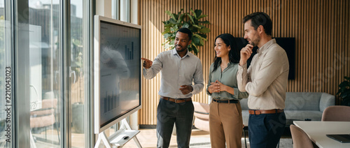 Diverse Business Team Reviewing Data on Interactive Screen