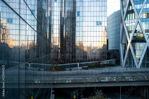 Reflections of contemporary buildings across a glass facade create layered geometric patterns and abstract modern architecture with strong visual structure