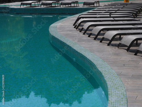 View of the infinity pool with sun loungers against the backdrop of the sea, and the hotel grounds.