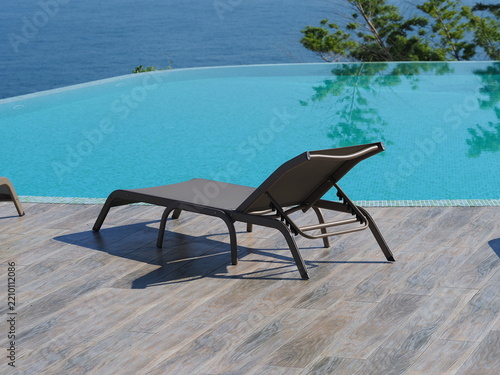 View of the infinity pool with sun loungers against the backdrop of the sea, and the hotel grounds.