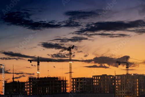 Construction site of modern residential buildings with cranes, colorful sunset sky, Moscow, Russia