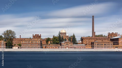 Old red brick factory architecture district on river bank, blurred clouds, Saint Petersburg, Russia