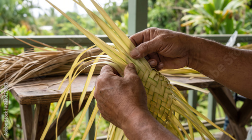 Close-Up Hands Weaving Yellow Palm Leaves Into Intricate Pattern