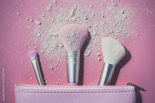 Make up brushes with powder on pink background
